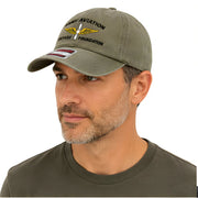 Green Army Aviation Heritage Foundation Dad Hat - SearchPify - Man wearing a green cap with text and logo on a white background