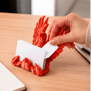 3D-Printed Business Card Holder - SearchPify - Red dragon-shaped paper towel holder with a hand pulling out a white sheet of paper on a wooden surface.