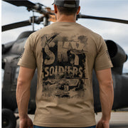 Person wearing a tan t-shirt with 'SHARK SOLDIERS' graphic design in front of a helicopter.